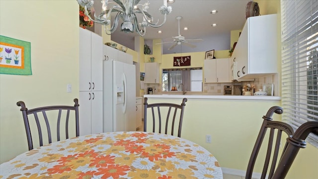 dining space with a wealth of natural light, sink, and ceiling fan with notable chandelier