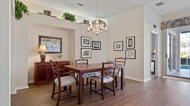 dining room with hardwood / wood-style floors, a textured ceiling, and an inviting chandelier