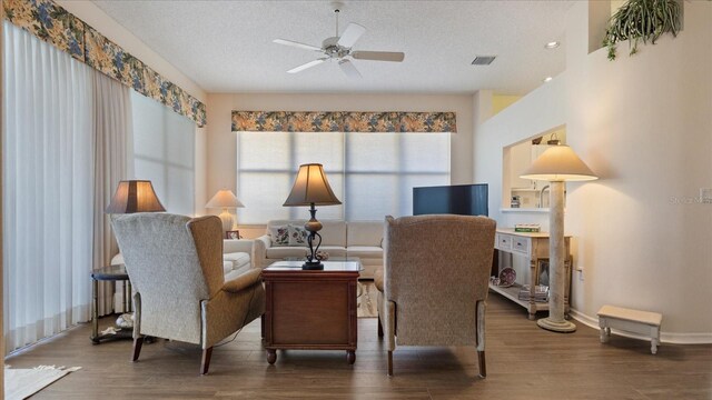 sitting room featuring a textured ceiling, dark hardwood / wood-style floors, plenty of natural light, and ceiling fan