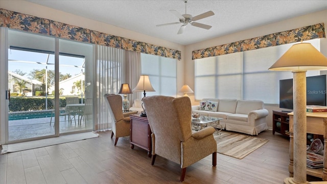 living room with hardwood / wood-style floors, ceiling fan, and a textured ceiling