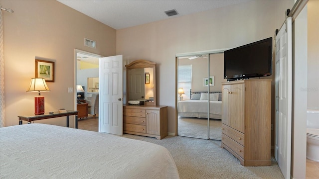 carpeted bedroom featuring a barn door and a closet