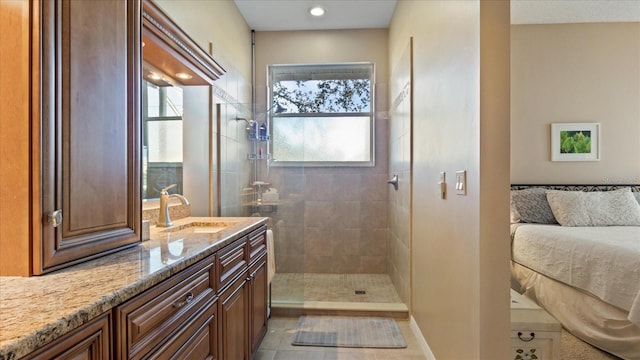 bathroom with tile patterned flooring, a tile shower, and vanity