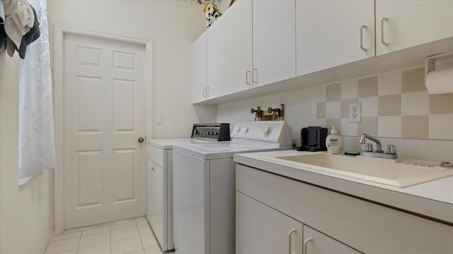 clothes washing area with cabinets, washing machine and dryer, light tile patterned flooring, and sink