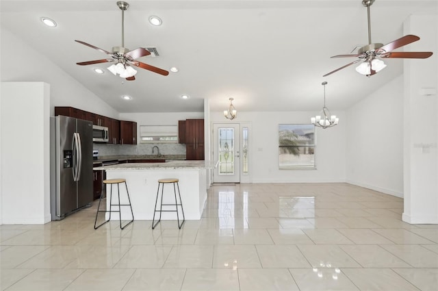 kitchen with a center island, vaulted ceiling, appliances with stainless steel finishes, a kitchen breakfast bar, and decorative backsplash