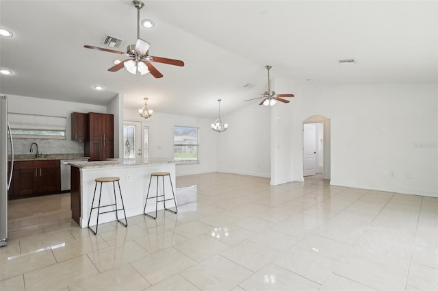 kitchen with vaulted ceiling, appliances with stainless steel finishes, sink, backsplash, and a center island