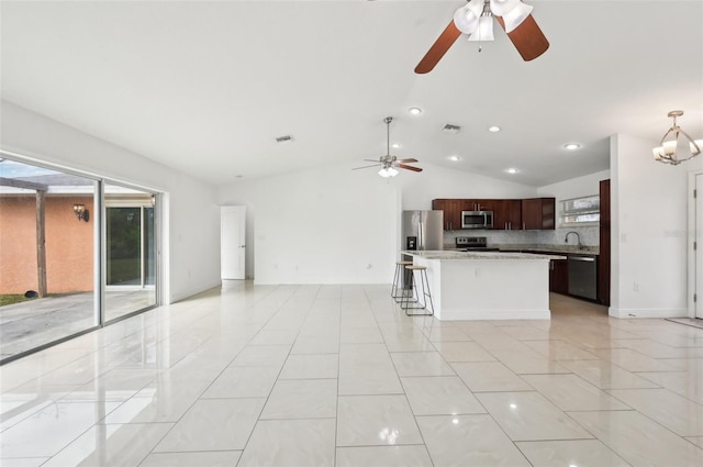 kitchen featuring lofted ceiling, a kitchen island, stainless steel appliances, tasteful backsplash, and a kitchen bar