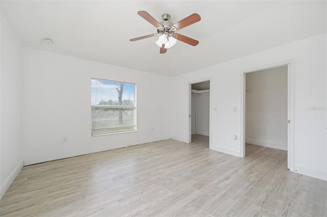 unfurnished bedroom featuring ceiling fan, light hardwood / wood-style flooring, a closet, and a walk in closet