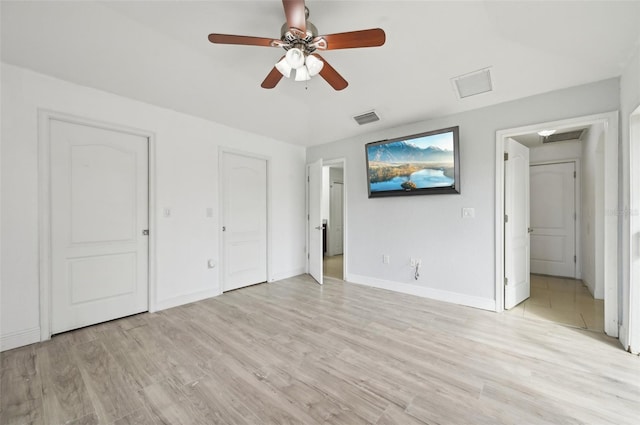 unfurnished bedroom with ceiling fan, ensuite bath, and light hardwood / wood-style flooring