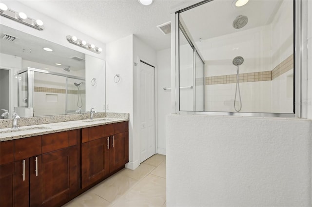 bathroom with walk in shower, vanity, tile patterned flooring, and a textured ceiling