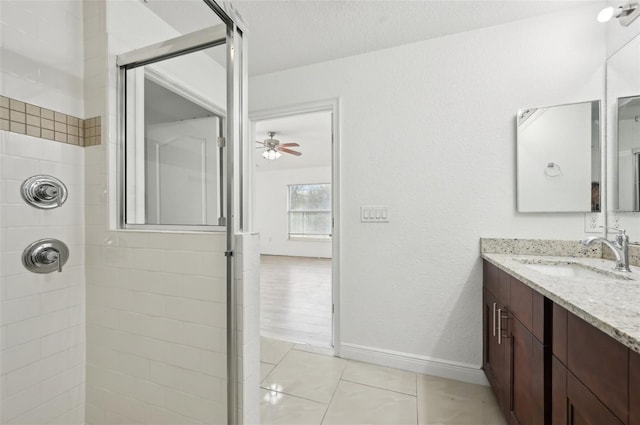 bathroom with a tile shower, tile patterned flooring, vanity, ceiling fan, and a textured ceiling