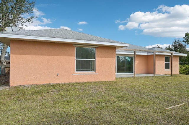 back of property with a lawn and a patio