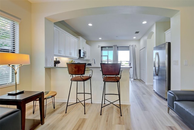 kitchen with a breakfast bar area, stainless steel appliances, kitchen peninsula, and white cabinets