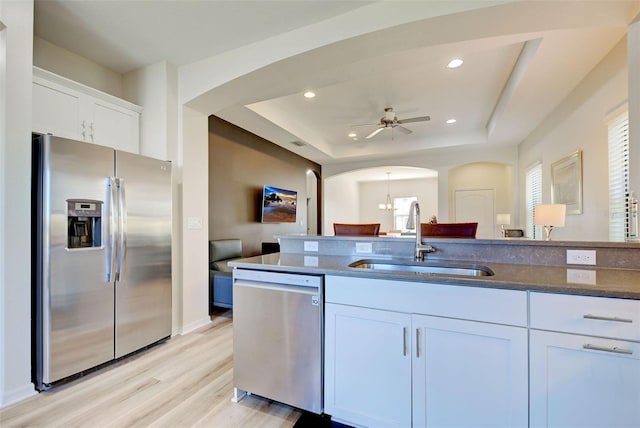 kitchen with sink, white cabinetry, a tray ceiling, stainless steel appliances, and light hardwood / wood-style floors
