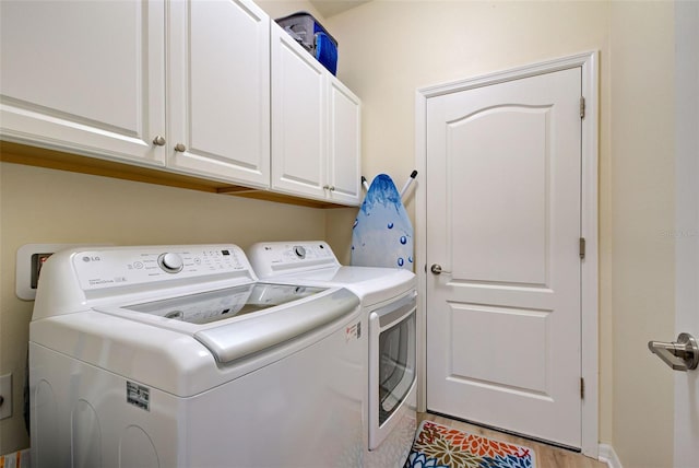 clothes washing area with washer and clothes dryer and cabinets