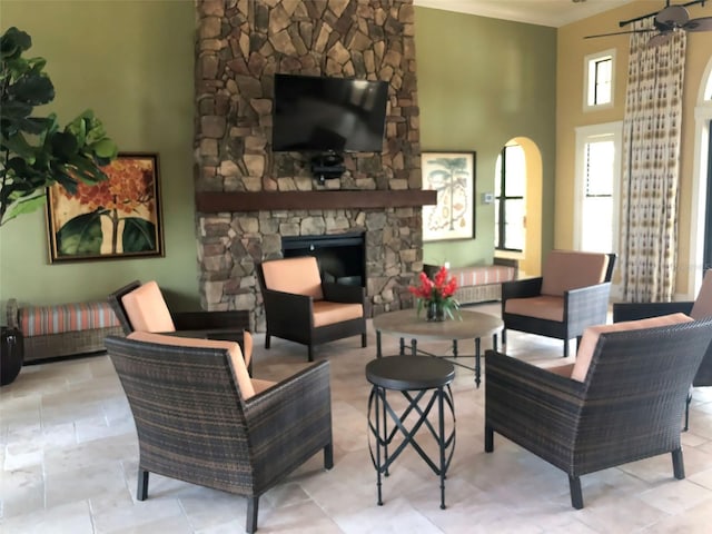 living room featuring a high ceiling, a fireplace, and ceiling fan