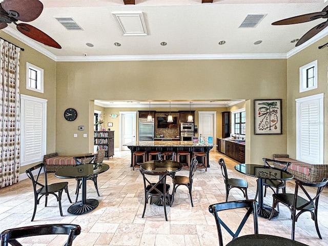 dining space with ceiling fan and ornamental molding