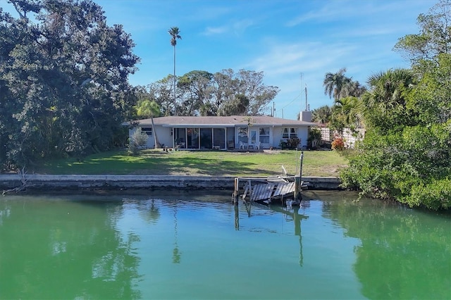 rear view of property featuring a lawn, a sunroom, and a water view