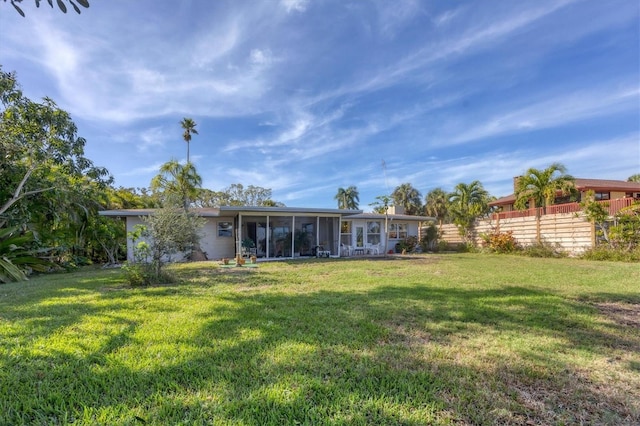 rear view of house featuring a sunroom and a yard