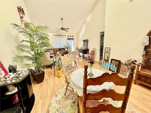 dining space with ceiling fan, a towering ceiling, and light hardwood / wood-style floors