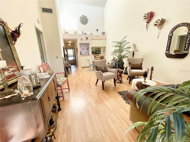 living room featuring a towering ceiling and light hardwood / wood-style flooring