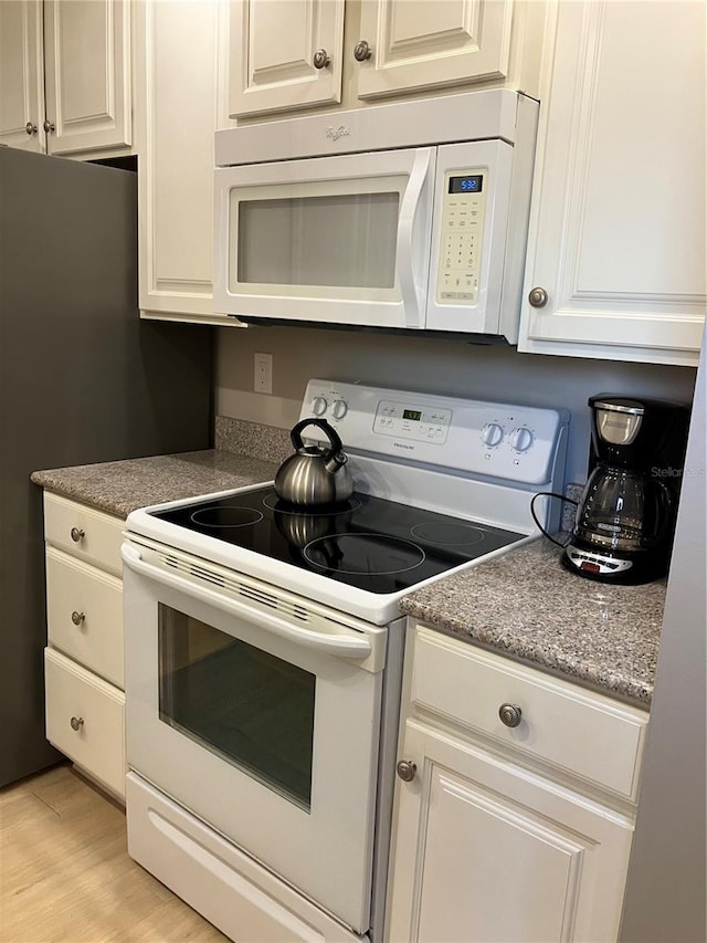 kitchen with white appliances, white cabinets, and light hardwood / wood-style flooring