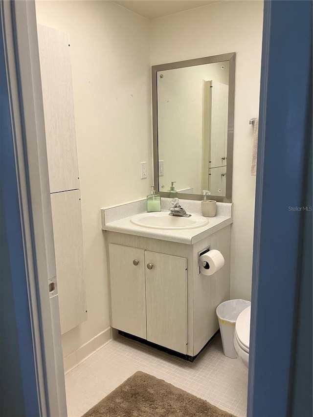 bathroom with toilet, vanity, and tile patterned floors