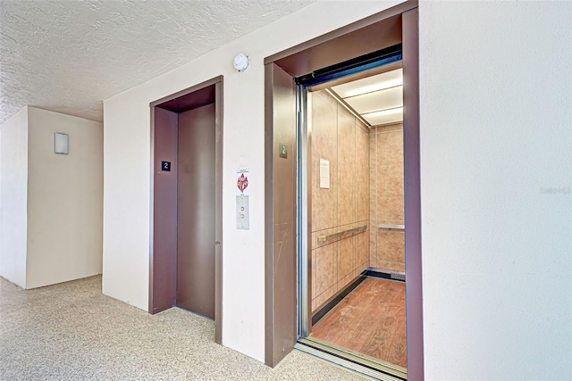 hall featuring elevator and a textured ceiling