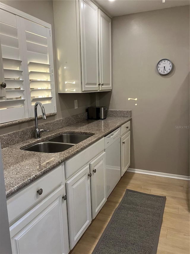 kitchen with sink, white cabinetry, light wood-type flooring, white dishwasher, and dark stone counters