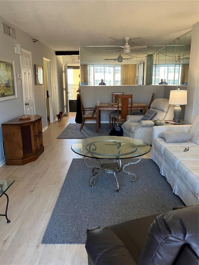 living room with hardwood / wood-style flooring, a textured ceiling, and ceiling fan