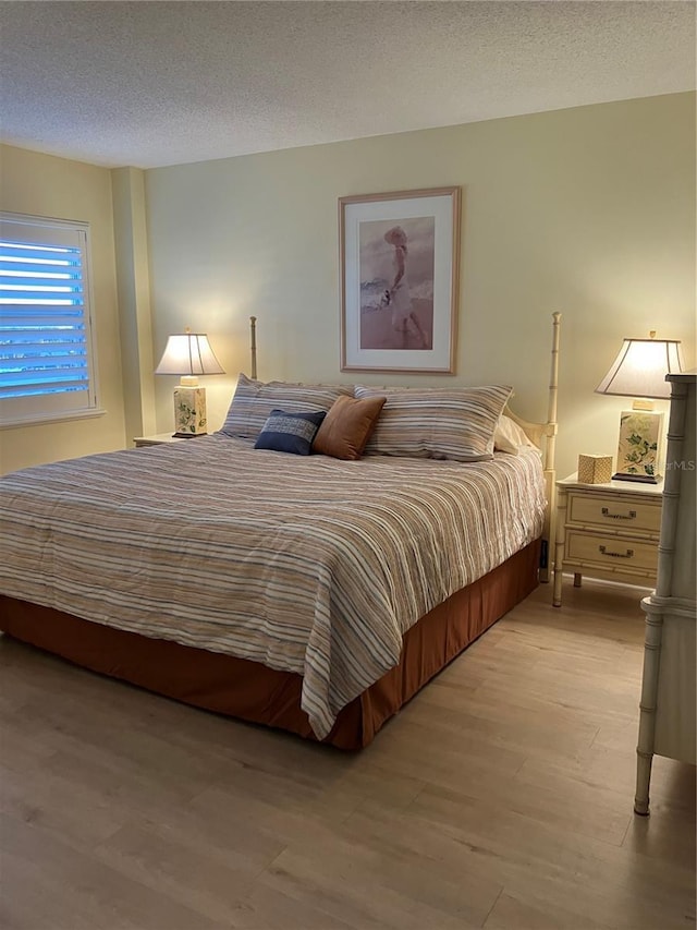 bedroom featuring a textured ceiling and light hardwood / wood-style flooring