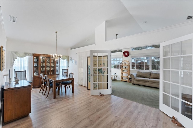 dining area with high vaulted ceiling, an inviting chandelier, light hardwood / wood-style floors, and french doors