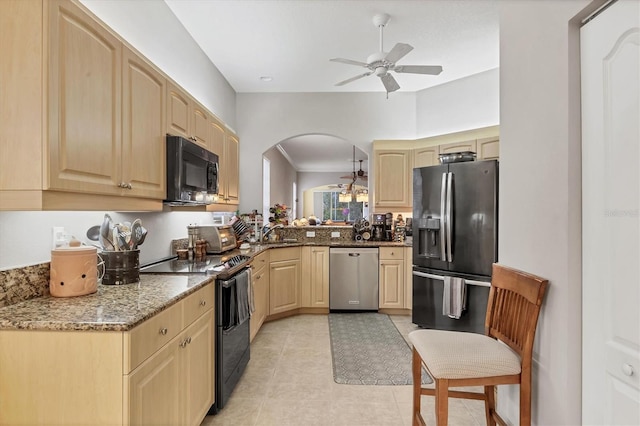 kitchen featuring ceiling fan, sink, stone countertops, decorative light fixtures, and black appliances