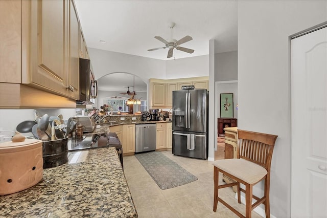 kitchen featuring ceiling fan, sink, stainless steel appliances, dark stone countertops, and light tile patterned flooring