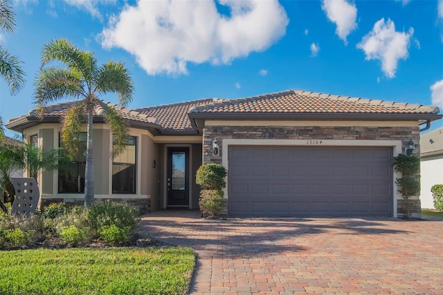 13164 Rinella St, Venice, FL 34293 - mediterranean / spanish-style home with a tile roof, stone siding, driveway, stucco siding, and a garage