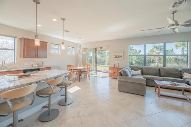 tiled living room featuring ceiling fan with notable chandelier and sink