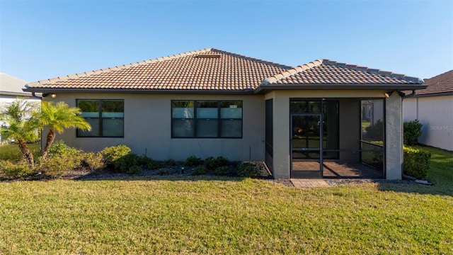 rear view of property featuring a sunroom and a lawn