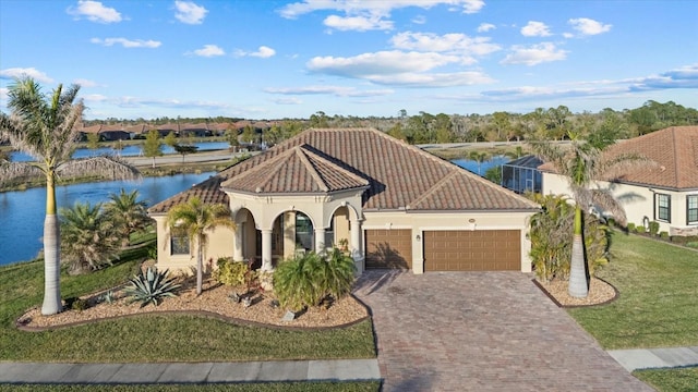 mediterranean / spanish house with a garage, a front yard, and a water view