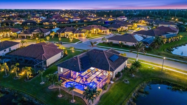 aerial view at dusk featuring a water view