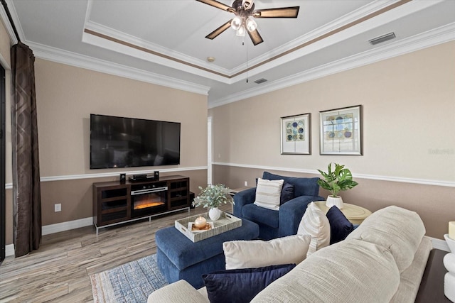 living room featuring ceiling fan, hardwood / wood-style floors, crown molding, and a raised ceiling