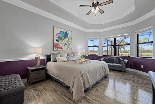 bedroom featuring ceiling fan, hardwood / wood-style floors, crown molding, and a raised ceiling