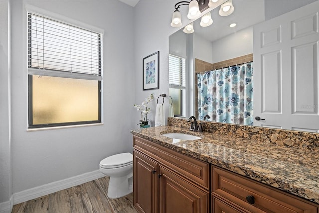 bathroom with toilet, a healthy amount of sunlight, wood-type flooring, and vanity