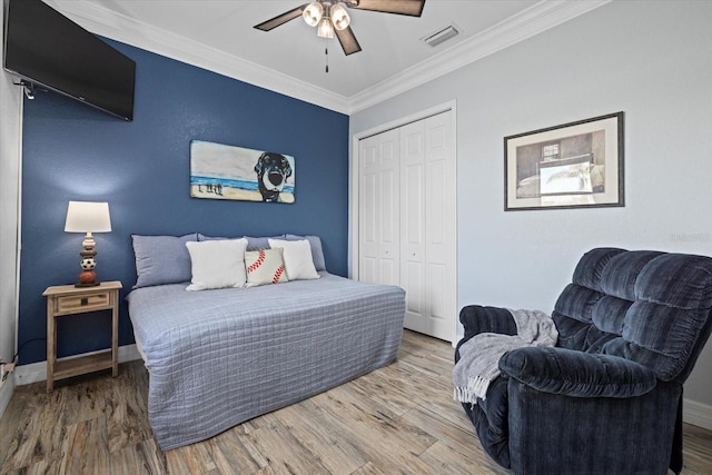 bedroom with ceiling fan, a closet, ornamental molding, and hardwood / wood-style floors