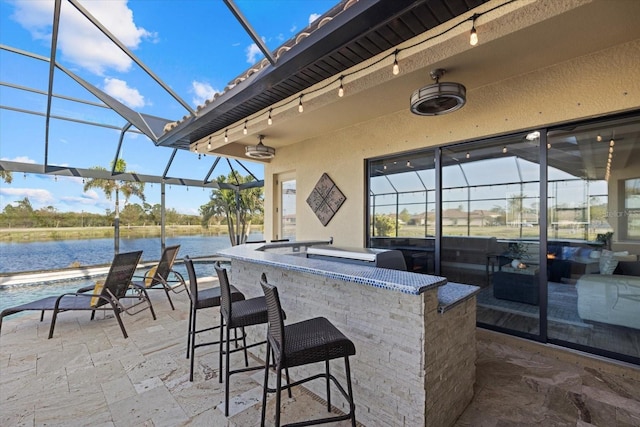 view of patio / terrace featuring an outdoor bar, a lanai, and a water view