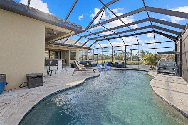 view of pool with glass enclosure, a patio area, a bar, and an outdoor living space