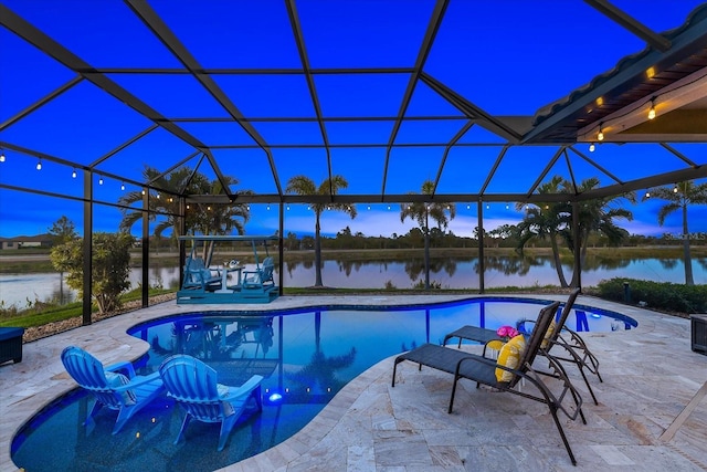 pool at dusk featuring glass enclosure, a water view, and a patio