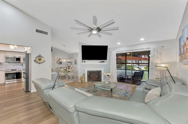 living room featuring ceiling fan, vaulted ceiling, and light hardwood / wood-style flooring