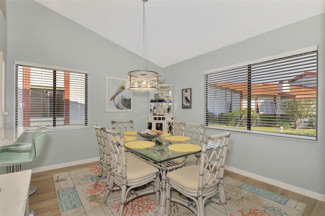 dining area with vaulted ceiling, a notable chandelier, and light hardwood / wood-style flooring