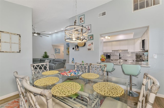 dining room featuring ceiling fan with notable chandelier and light hardwood / wood-style flooring