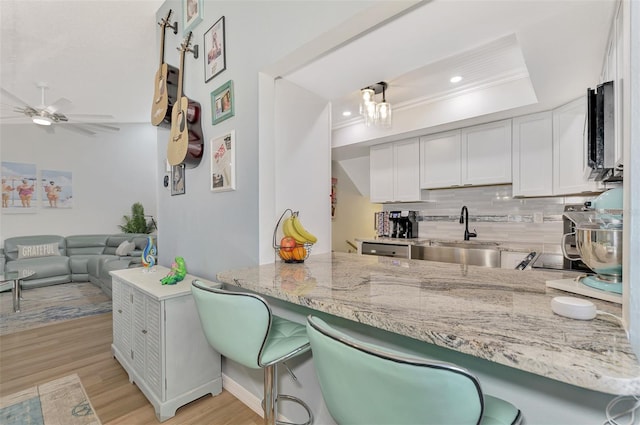 kitchen featuring white cabinets, sink, backsplash, and kitchen peninsula