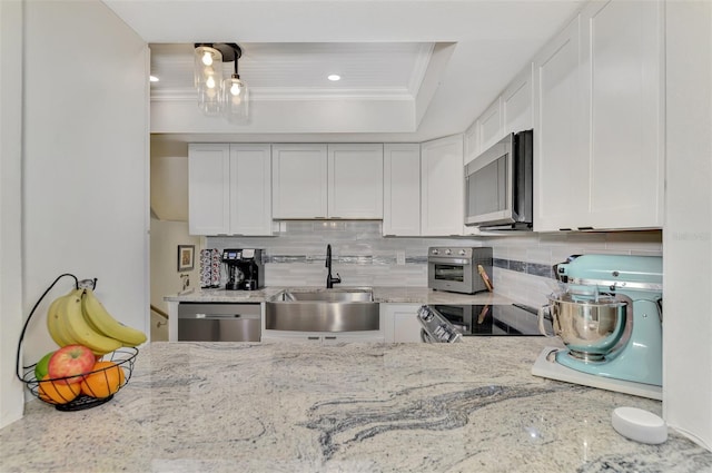 kitchen with tasteful backsplash, crown molding, white cabinetry, appliances with stainless steel finishes, and sink